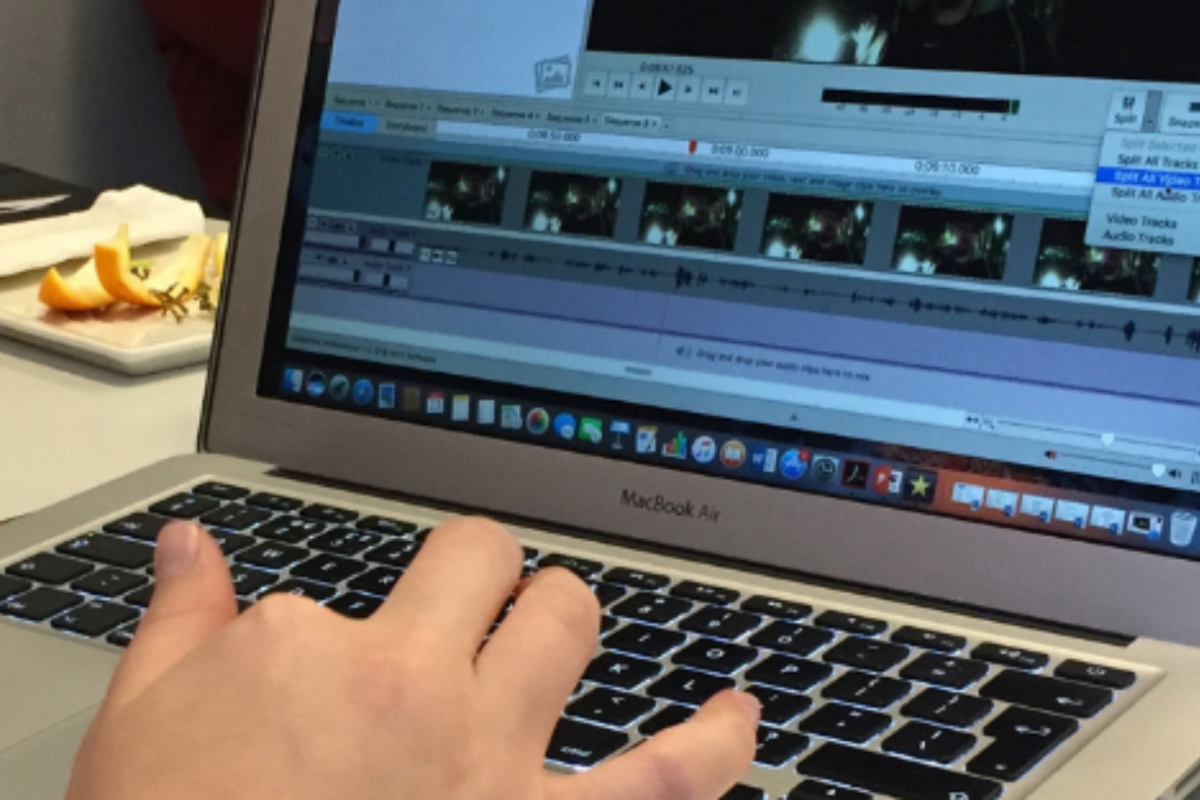 A hand uses a laptop to edit a video